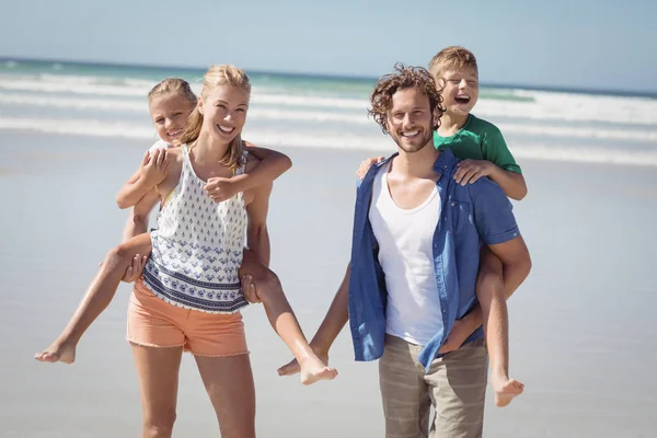 Pais piggybacking seus filhos na praia — Fotografia de Stock