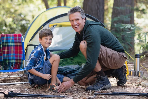 Father and son kneeling by tent in forest — Stock Photo, Image