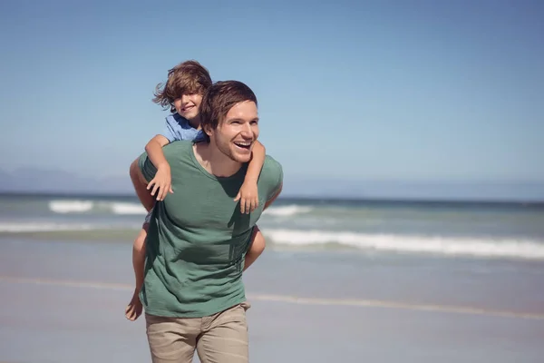 Vader meeliften zijn zoon op strand — Stockfoto