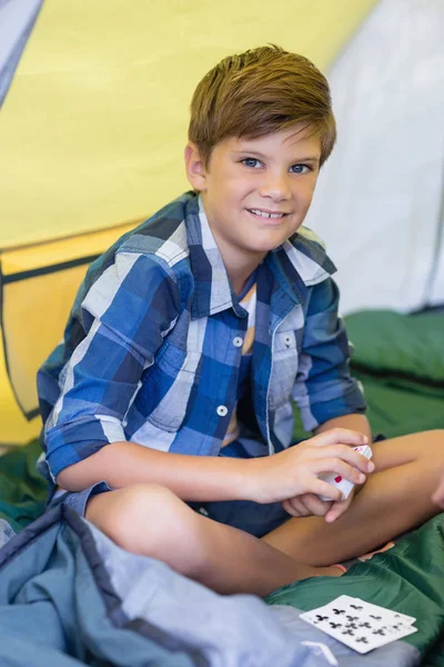 Boy playing cards while sitting in tent — Stock Photo, Image