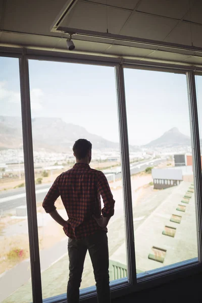 Empresário olhando através da janela de vidro — Fotografia de Stock