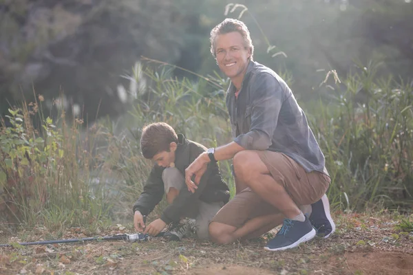 Père assis par fils avec canne à pêche — Photo