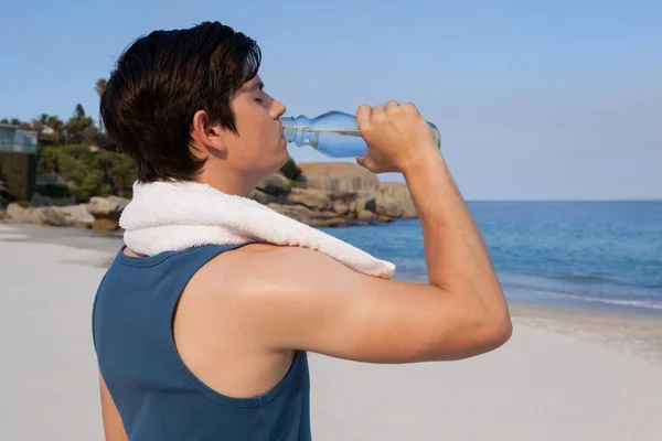 Man dricksvatten från flaska på stranden — Stockfoto