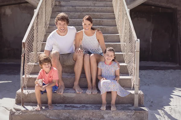 Família sorridente sentada na escada — Fotografia de Stock