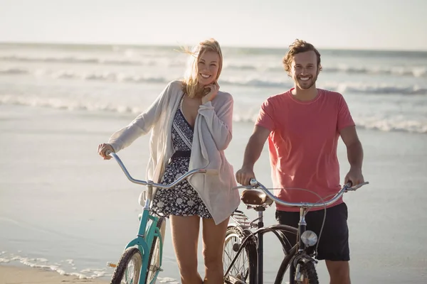 Pareja con bicicletas de pie en la playa — Foto de Stock