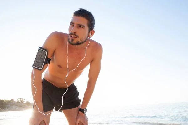 Man het nemen van een pauze na het joggen op strand — Stockfoto