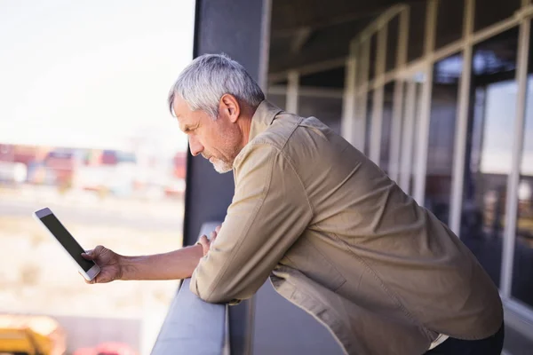 Зрелый бизнесмен с планшетным ПК на балконе — стоковое фото