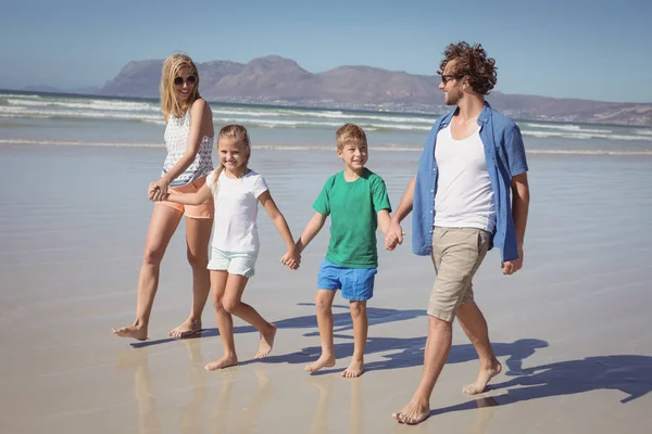 Famiglia che si tiene per mano mentre cammina in spiaggia — Foto Stock