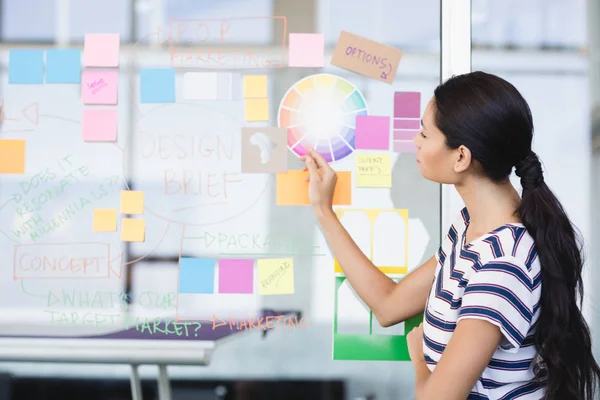 Geschäftsfrau blickt auf Plan an Wand — Stockfoto