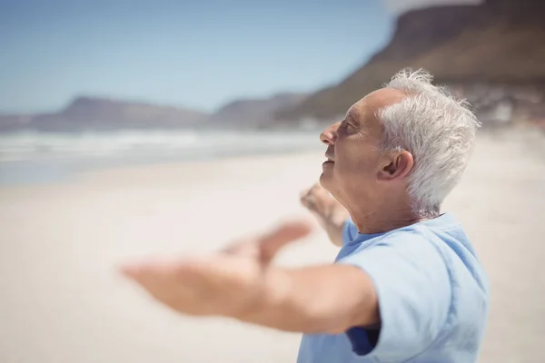 Senior man met armen gestrekt op strand — Stockfoto