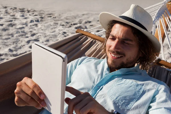 Mann entspannt sich auf Hängematte und benutzt Tablette — Stockfoto