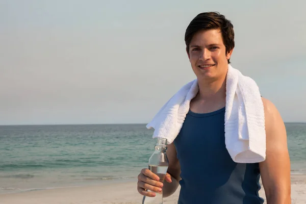 Mannen innehar vattenflaska på stranden — Stockfoto