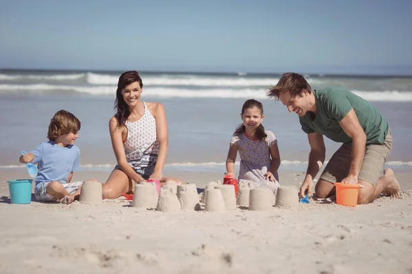 Οικογένεια κάνοντας κάστρο φτιαγμένο από άμμο στην παραλία — Φωτογραφία Αρχείου
