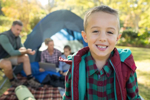 Menino sorrindo enquanto a família está sentada na tenda — Fotografia de Stock