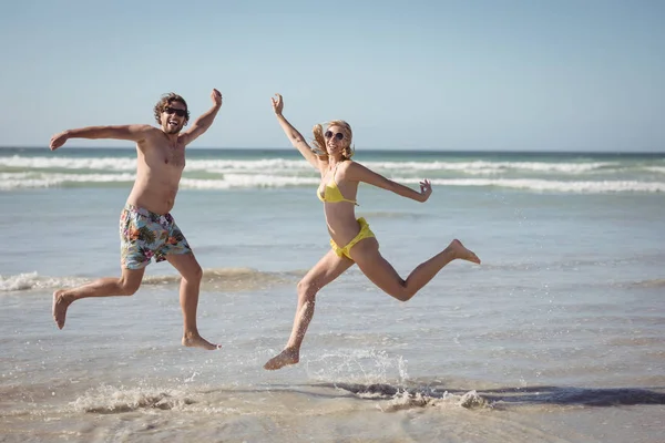 Vrolijke paar springen op de kust bij strand — Stockfoto