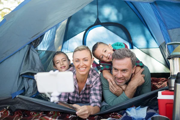 Famiglia sorridente che prende selfie nella tenda — Foto Stock