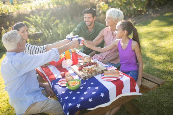 Familie stößt beim Essen auf die Tassen an — Stockfoto