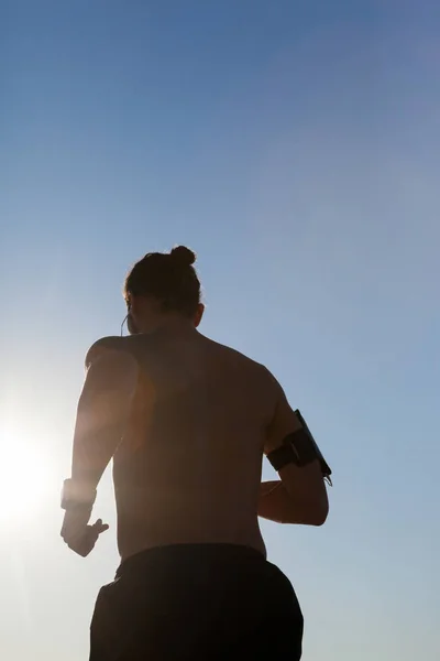 Человек бегает по пляжу на фоне голубого неба — стоковое фото