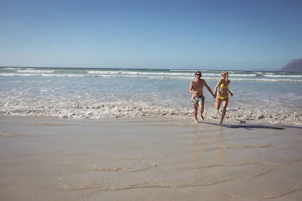 Casal correndo em terra na praia — Fotografia de Stock