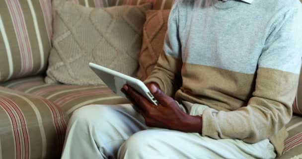 Старший мужчина с помощью цифрового планшета в гостиной — стоковое видео