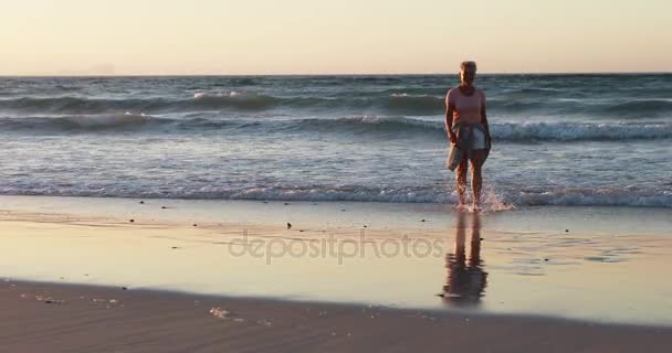 Seniorin geht am Strand spazieren — Stockvideo