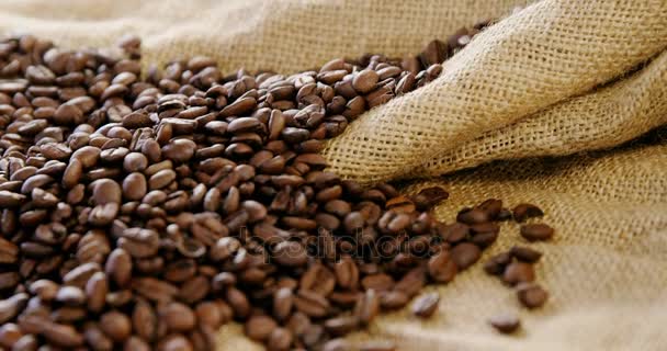 Roasted coffee beans on sack textile — Stock Video