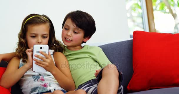 Broers en zussen gebruik mobiele telefoon in woonkamer — Stockvideo