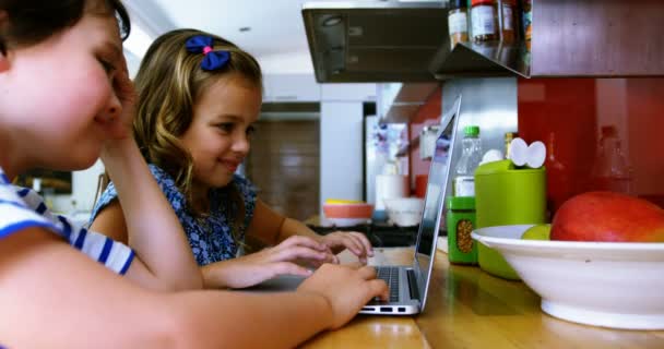 Братья и сестры с помощью ноутбука на кухне — стоковое видео
