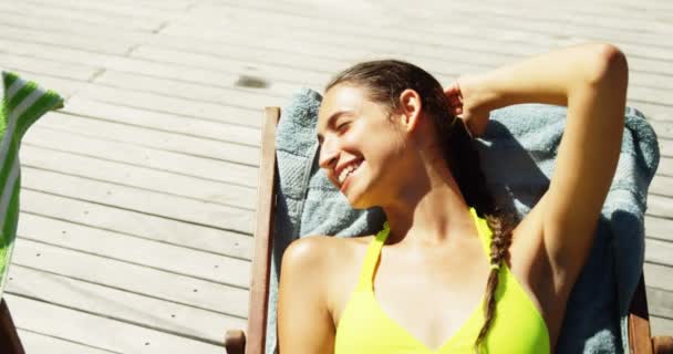 Zwei Frauen interagieren miteinander beim Sonnenbaden in der Nähe eines Swimmingpools — Stockvideo