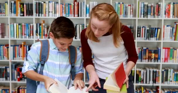 Lächelnde Schüler lesen Buch in Bibliothek — Stockvideo