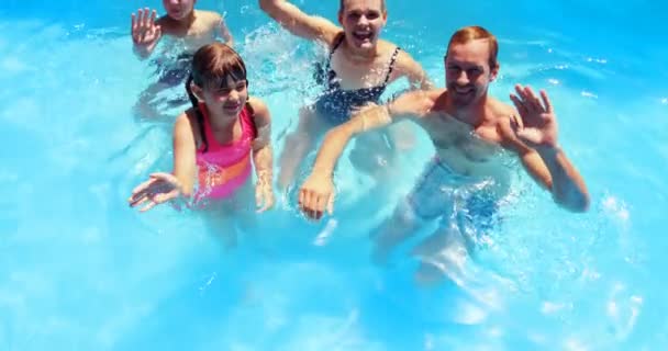 Porträtt av lycklig familj viftande hand i poolen — Stockvideo