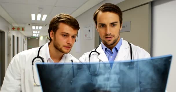 Врачи изучают рентгеновский отчет в коридоре — стоковое видео