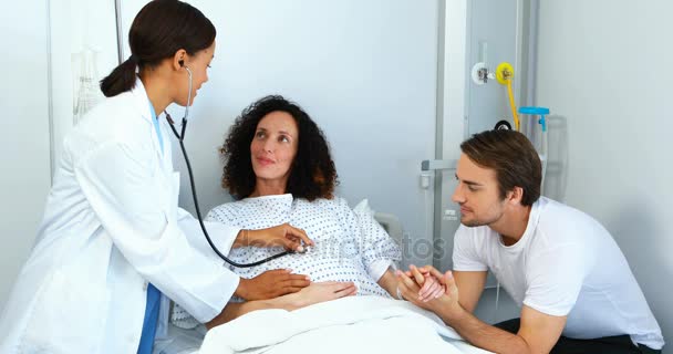 Médico examinando a una mujer embarazada con estetoscopio en la sala — Vídeo de stock