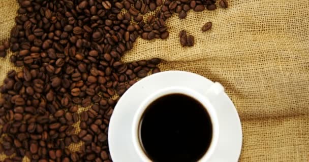 Tazza di caffè e fagioli tostati su tessuto sacco — Video Stock