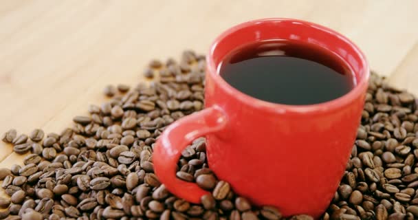 Schwarzer Kaffee umgeben von gerösteten Bohnen — Stockvideo