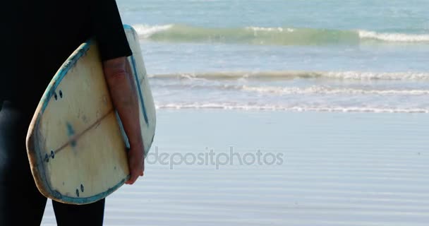 Ανώτερος άνθρωπος με μόνιμη σανίδα του σερφ στην παραλία — Αρχείο Βίντεο