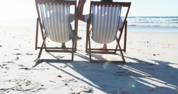 Senioren-Paar entspannt auf Liegestühlen am Strand — Stockvideo