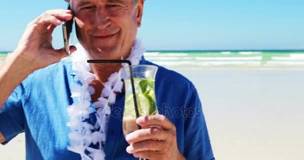 Старший разговаривает по мобильному телефону на пляже — стоковое видео