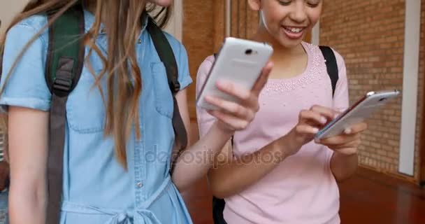 Feliz colegialas utilizando el teléfono móvil en la cancha de baloncesto — Vídeo de stock