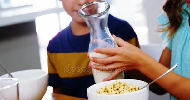 Κορίτσι ρίχνει γάλα στο μπολ δημητριακών στην κουζίνα — Αρχείο Βίντεο
