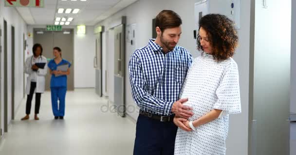 Чоловік взаємодіє з вагітною жінкою в коридорі — стокове відео