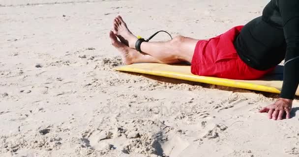 Hombre mayor con tabla de surf relajante en la playa — Vídeo de stock