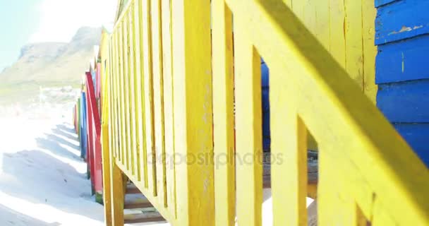 Girl reading book near colorful beach hut — Stock Video