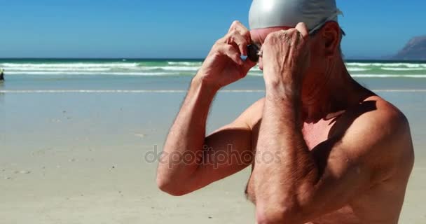 Homem sênior usando óculos de natação na praia — Vídeo de Stock