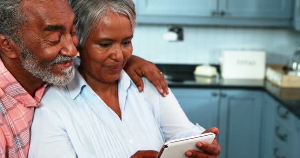 Старшая пара с помощью цифрового планшета на кухне — стоковое видео