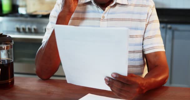 Uomo anziano guardando il documento che parla sul telefono cellulare — Video Stock