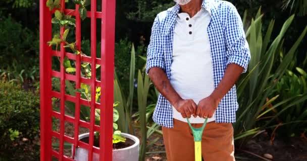 Senior man holding gardening equipment in backyard — Stock Video