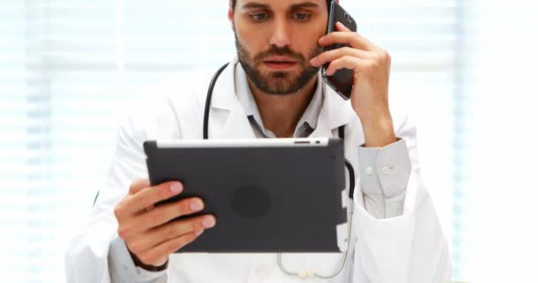 Médico masculino hablando por teléfono móvil mientras usa tableta digital — Vídeo de stock