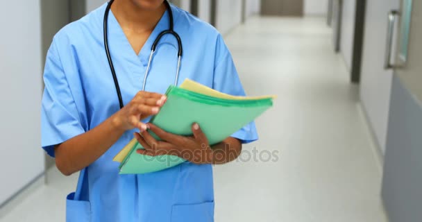 Médico sonriente con informe médico parado en el pasillo — Vídeos de Stock