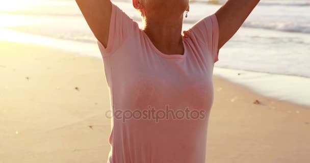 Mujer mayor de pie con los brazos extendidos en la playa — Vídeos de Stock